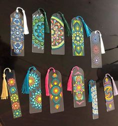 several bookmarks with different designs and tassels hanging from them on a table