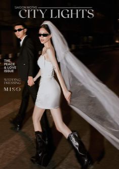 a man and woman are walking down the street in their wedding attire, with veil blowing in the wind