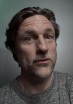 a man is looking at the camera while wearing a gray shirt