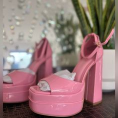 a pair of pink high heeled shoes sitting on top of a table next to a potted plant