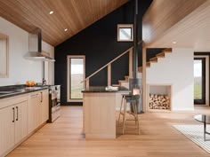 an open kitchen and living room area with wood flooring, black walls and ceiling