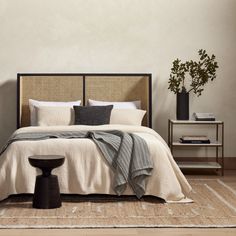 a bedroom with a bed, side table and potted plant on the floor next to it