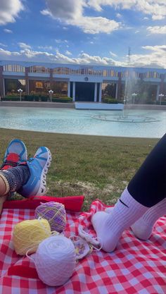 a person laying on top of a red and white checkered blanket next to a pool