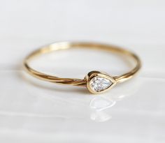 a gold ring with a single diamond on the top, sitting on a white surface