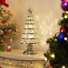 a lighted christmas tree sitting on top of a white mantle next to a decorated christmas tree