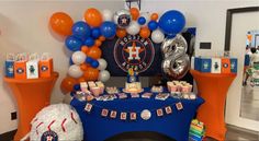 an orange, white and blue baseball themed party with balloons on the wall in the background