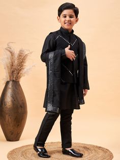 Vastramay Boy's Black Mirror Work Jacket And Solid Kurta Pyjama Set With Black Ethnic Dupatta A stylish and traditional ensemble for boys, this set features a black mirror work jacket paired with a solid kurta pyjama set and a black ethnic dupatta. The jacket is intricately designed with mirror work, adding a touch of elegance. The kurta and pyjama are solid black, complementing the jacket perfectly. The set is perfect for festive occasions and celebrations. Features: Includes jacket, kurta, pyj Black Nehru Jacket With Zari Work For Festivals, Black Nehru Jacket With Zari For Festivals, Black Long Sleeve Winter Kurta, Black Fitted Long Sleeve Traditional Wear, Straight Kurta For Eid Festivities, Straight Kurta Outerwear For Eid, Ceremonial Kurta With Traditional Patterns And Long Sleeves, Traditional Fitted Kurta For Festivals, Black Nehru Jacket With Traditional Drape For Festive Occasions