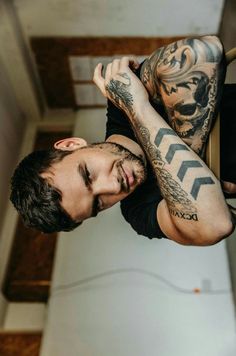 a man with tattoos on his arms and chest is looking up at the camera while he holds