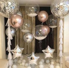 some silver and white balloons are hanging from the ceiling in front of a wall with stars