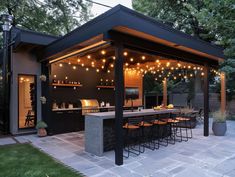 an outdoor kitchen with lights on the roof and bar area in the middle of it