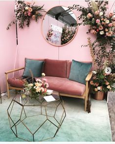 a living room filled with furniture and flowers on the wall next to a round mirror