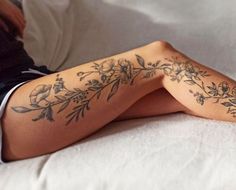 a woman laying on top of a bed next to a white sheet covered in tattoos