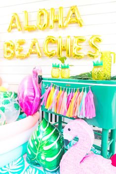 a party table with flamingos, tassels and balloons on the tables for an aloha beach party