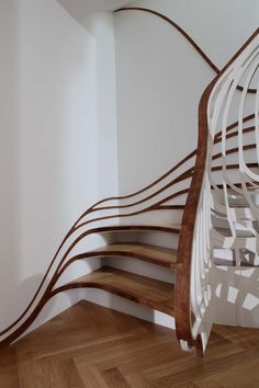 a spiral staircase with wooden handrails and white walls in an empty room that has wood parquet flooring