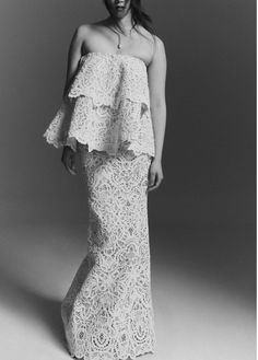 a woman in a white lace dress posing for a black and white photo with her hands on her hips