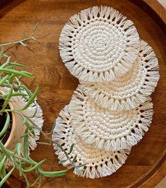 two white crocheted doily sitting on top of a wooden tray next to a potted plant