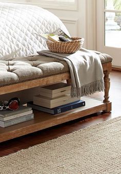 a wooden bench with books on top of it in front of a window and rug