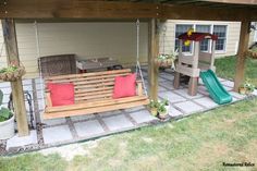 a wooden swing set sitting under a pergoline covered patio with red pillows on it