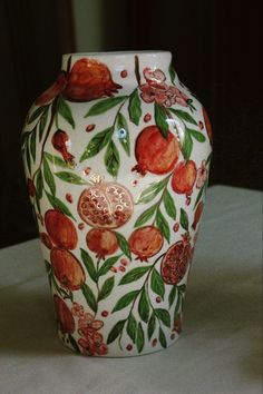 a white vase with red and green designs on it's sides sitting on a table