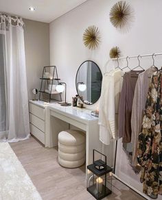 a white dressing room with clothes hanging on the rack and candles in front of it