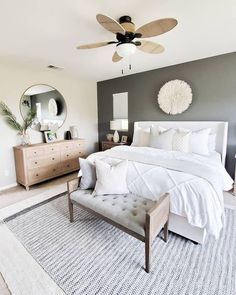 a white bed sitting in a bedroom next to a dresser and mirror on top of a rug