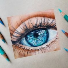 a drawing of an eye with colored pencils next to it