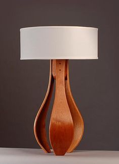 a wooden table lamp with a white lampshade on the top and bottom part