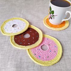 three crocheted coasters sitting next to a cup of coffee