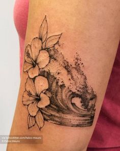 a woman's arm with flowers on it and waves in the water behind her