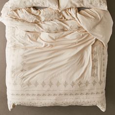 an unmade bed with white sheets and pillows