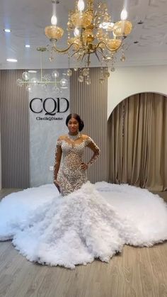 a woman standing in front of a dress made out of fluffy white fabric and feathers