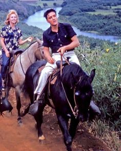 two people riding horses down a dirt path