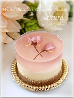 a small cake with pink frosting and flowers on the top is sitting on a gold plate