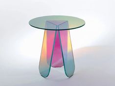 a colorful glass table with curved legs on white background in front of a light colored backdrop