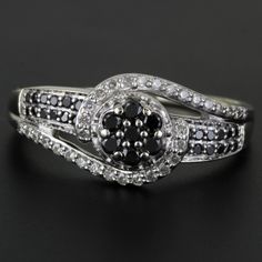 an elegant black and white diamond ring on a black surface with the center stone surrounded by smaller diamonds