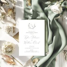 an elegant wedding card with flowers and greenery on the side, surrounded by satin fabric