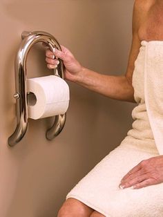 a woman in a bathrobe holding a roll of toilet paper next to a towel rack