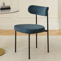 a blue chair sitting on top of a carpeted floor next to a white table