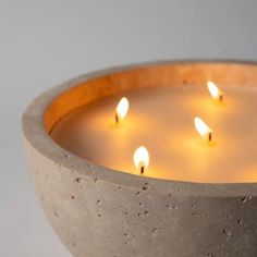 several lit candles in a concrete bowl