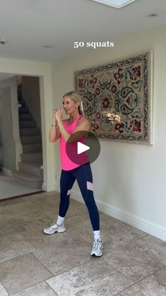 a woman in a pink top and blue leggings is dancing