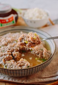 a spoon full of soup with meatballs in it and some other ingredients on the side