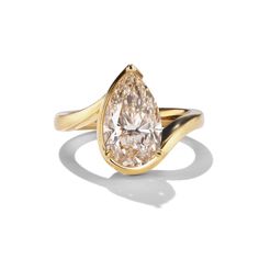 a yellow gold ring with a pear shaped diamond in the center and a curved band around it