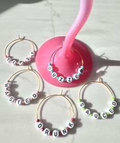 a pink toothbrush sitting on top of a table next to four hoops with name beads