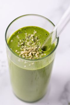 a green smoothie is in a glass with a straw and garnishes