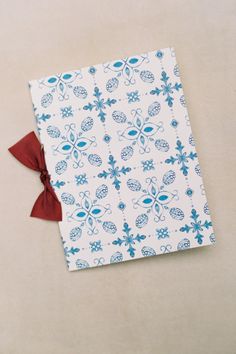 a blue and white book with a red bow on the cover sitting on a table