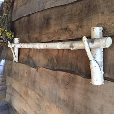 a white pipe is attached to the side of a wooden wall with flowers growing on it