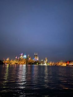 the city skyline is lit up at night as seen from across the water with bright lights