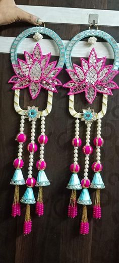 two pink and blue earrings hanging on a wall