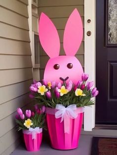 two pink flower pots with flowers in them and a bunny mask on the front door