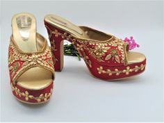 Our new collection of wedding shoes which we offer for you. These feature zardozi hand embroidered design on raw silk fabric. They are a red with beautiful design imbedded with gold rhinestones and gold zari work in the shape of leaves along with zari and gold rhinestones border on platform base. They feature a round toe chunky heel design. They have a heel design measuring 5 inches from bottom of heel to top of heel and platform base in front of 1 inch. They are comfortable to wear all day. The Traditional High Heel Festive Heels, Traditional High Heels For Festive Occasions, Traditional Open Toe Wedding Heels, Traditional Open Toe Heels For Festive Occasions, Festive Open Toe Wedding Shoes, Festive High Heels For Wedding, Traditional Wedding Heels With Handwork, Festive Wedding High Heels, Traditional Open Toe Heels For Party